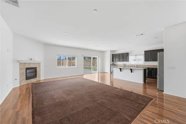 a large white kitchen with kitchen island a sink wooden floor and a fireplace