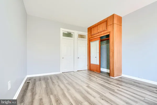 a view of an empty room with wooden floor and closet