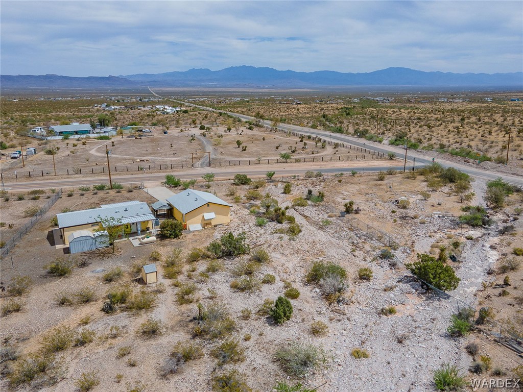 2465 Egar Road Golden Valley, AZ 86413 - Photo 82 of 98 The property features a desert landscape with distant mountains, a single-story residence, and an additional detached structure