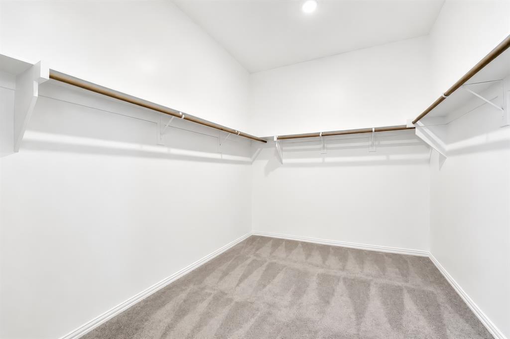 3610 Scotsman Road Sachse, TX 75048 - Photo 27 of 34 Recessed lighting illuminating a spacious closet with light gray carpeting, white walls, and built-in shelving with hanging rods