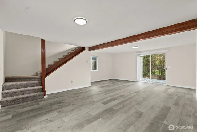 a view of an empty room with wooden floor and stairs