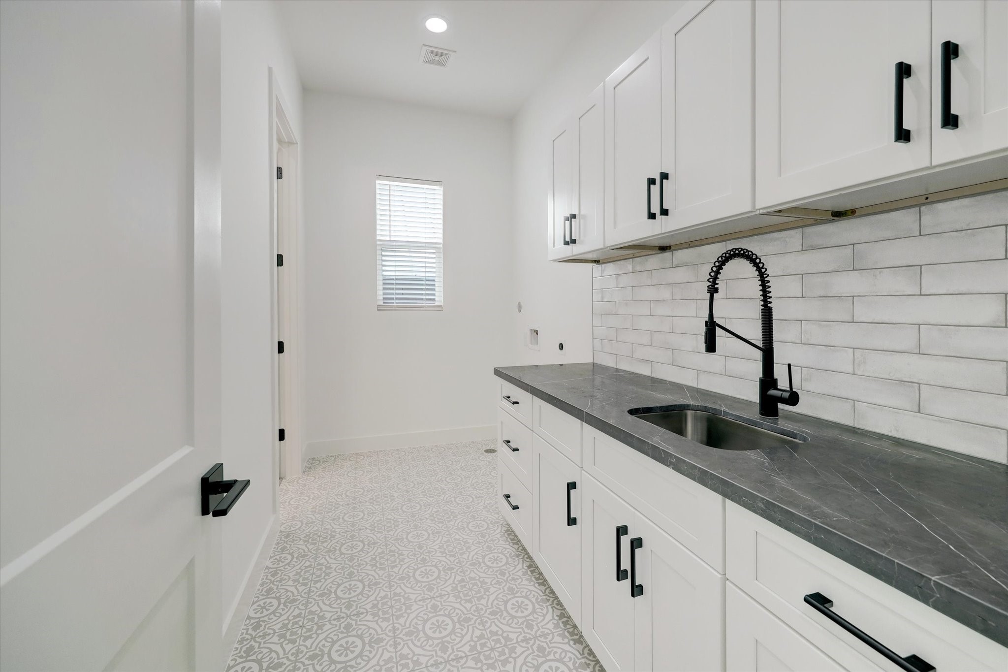 6209 Westcott Street Houston, TX 77007 - Photo 13 of 16 Utility Room – features custom built-ins and a utility sink, along with dual access from both the hallway and the primary closet.