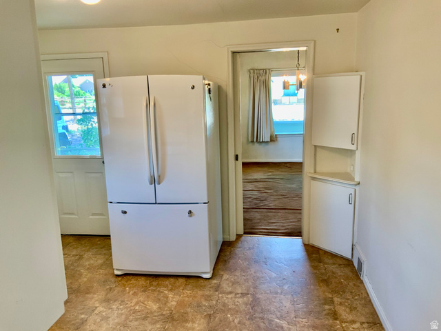 630 North Main Street Monroe, UT 84754 - Photo 6 of 63 Kitchen featuring freestanding refrigerator, healthy amount of natural light, stone finish flooring, and white cabinets