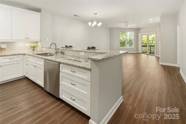 a kitchen with granite countertop a stove a sink and white cabinets with wooden floor