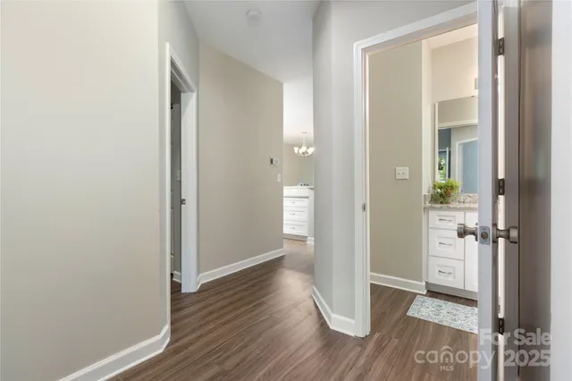 a view of a hallway with wooden floor and a bathroom