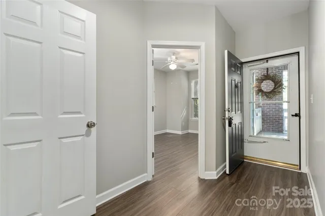 a view of a hallway with wooden floor and a bathroom