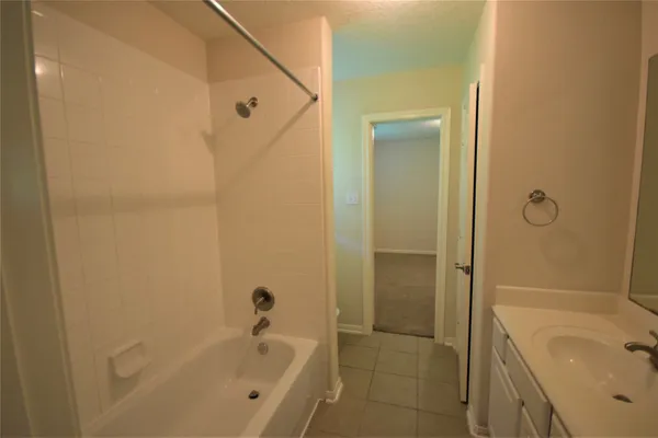 a bathroom with a tub shower sink and vanity