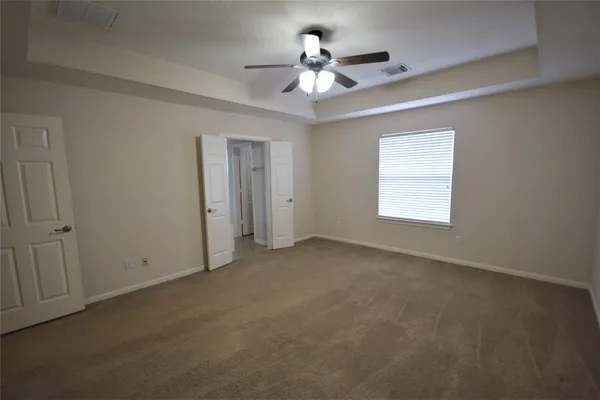 an empty room with a chandelier fan and windows