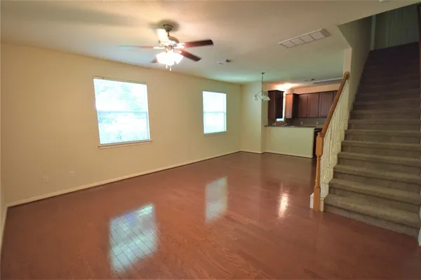 a view of a livingroom with wooden floor and a ceiling fan