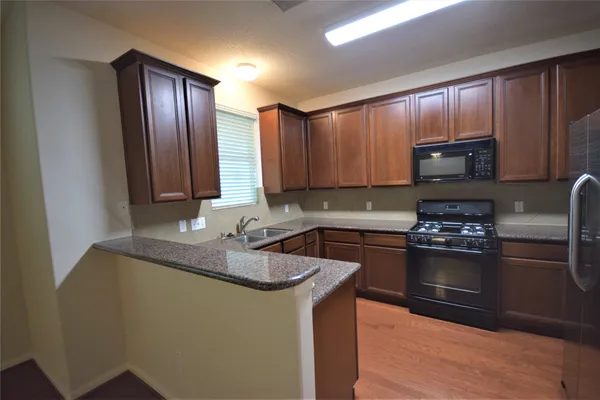 a kitchen with granite countertop wood cabinets stainless steel appliances and a sink