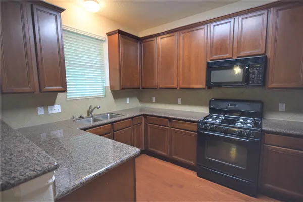 a kitchen with granite countertop wood cabinets stainless steel appliances and a sink