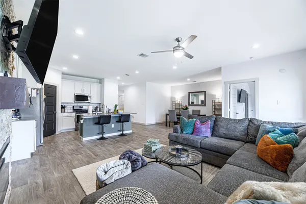 a living room with furniture kitchen view and a chandelier