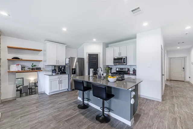 a kitchen with a refrigerator a stove top oven a sink dishwasher and white cabinets with wooden floor