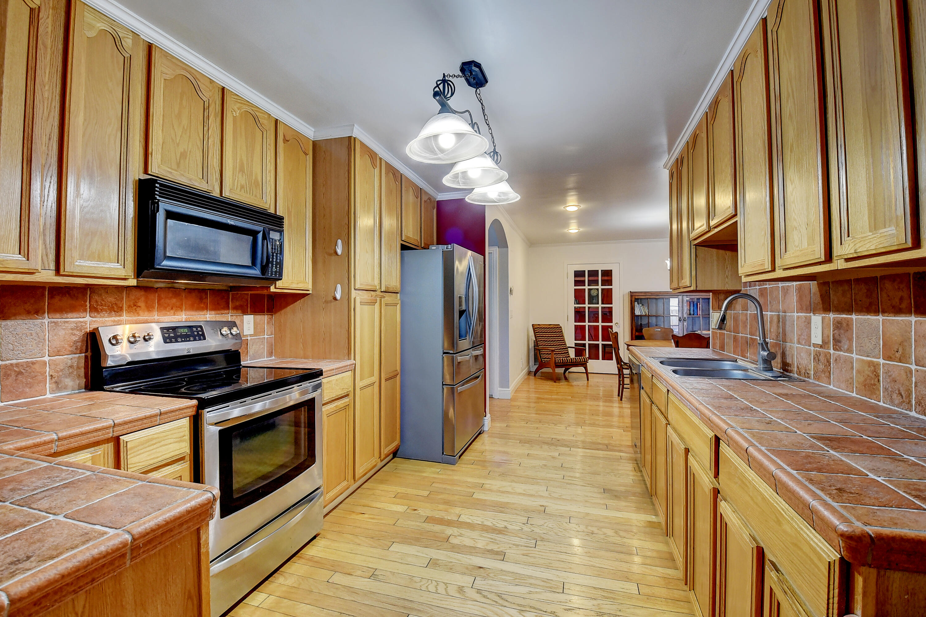1775 Southwest 8th Street Boca Raton, FL 33486 - Photo 11 of 20 a kitchen with stainless steel appliances granite countertop a refrigerator a stove top oven a sink dishwasher and wooden cabinets with wooden floor