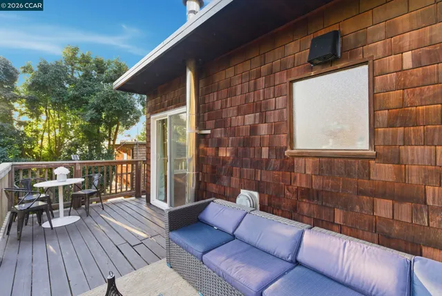 a view of a patio with couches and table and chairs with wooden floor and fence