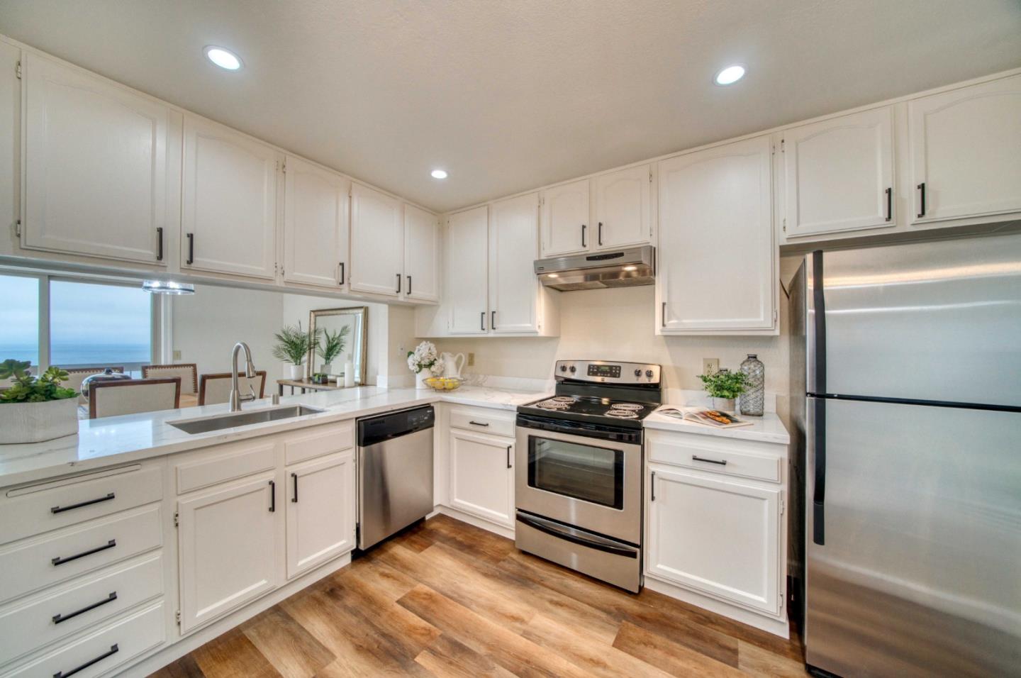 a kitchen with cabinets stainless steel appliances a sink and wooden floor