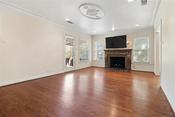 an empty room with wooden floor a fireplace and a window