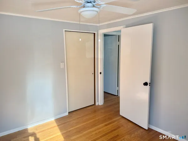 a view of a room with wooden floor and a ceiling fan