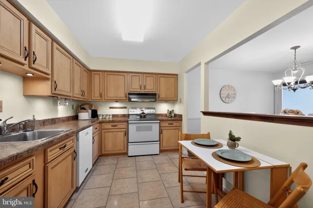 a kitchen with stainless steel appliances kitchen island granite countertop a sink dishwasher a stove a refrigerator with a dining table and chairs