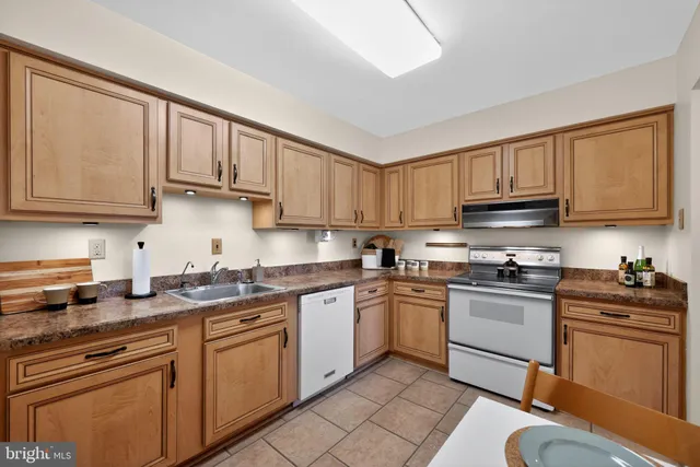 a kitchen with stainless steel appliances granite countertop a sink stove refrigerator and cabinets