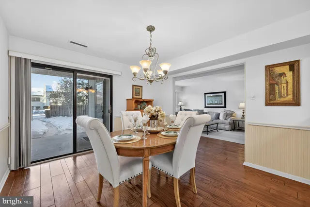 a dining room with wooden floor a chandelier a glass table and chairs