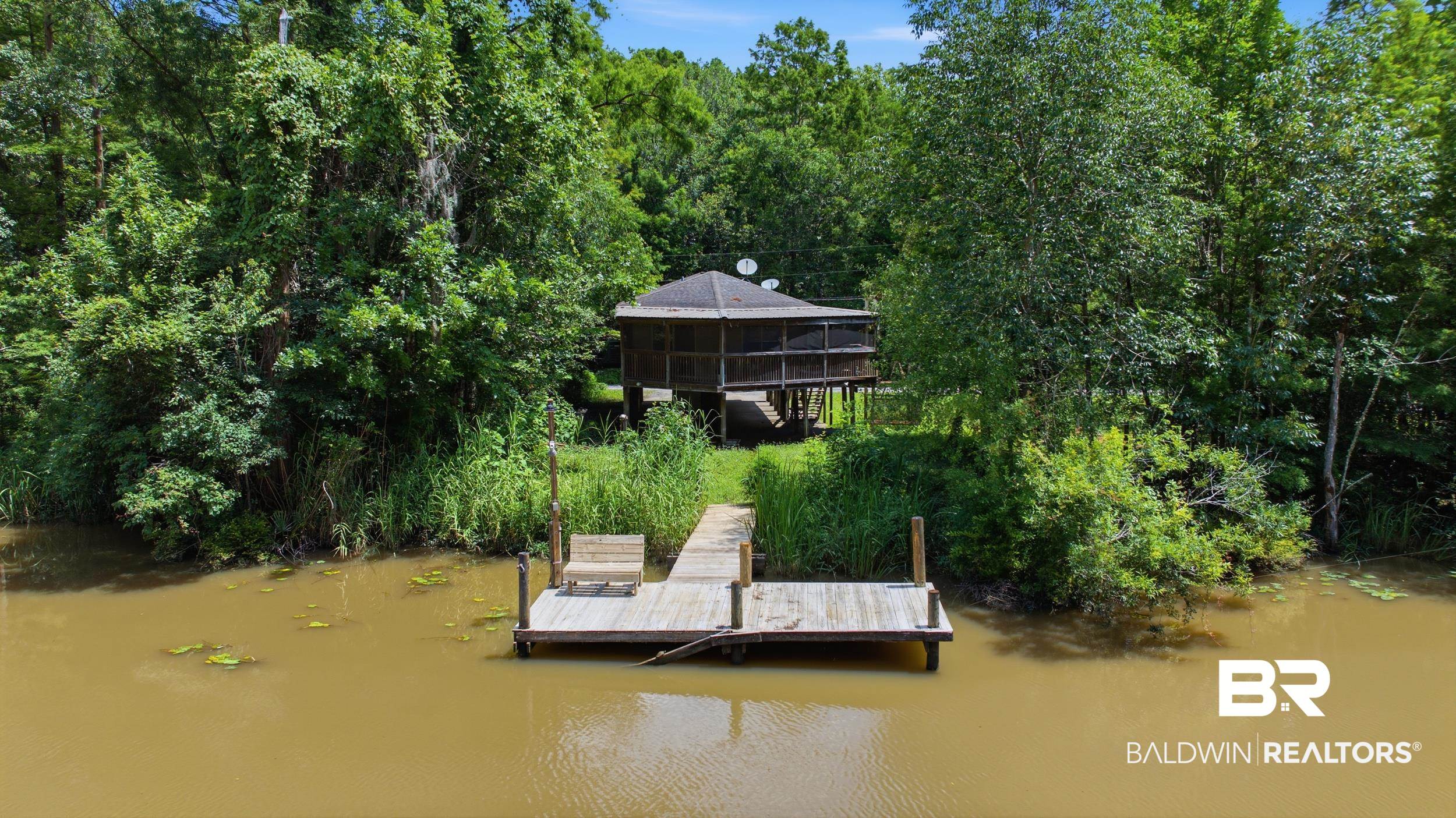 42080 Bayou Road Bay Minette, AL 36507 - Photo 42 of 43 Waterfront property featuring a wooden dock with built-in seating, a screened gazebo on stilts, and lush surrounding foliage