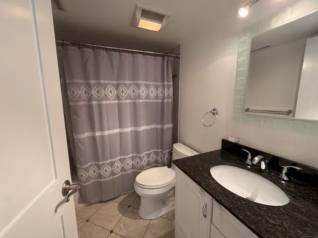 a bathroom with a granite countertop sink toilet a mirror and shower