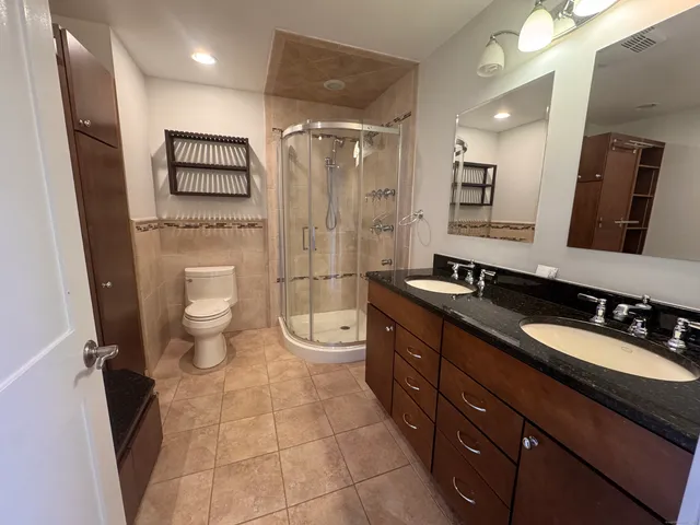 a bathroom with a double vanity sink toilet mirror and shower