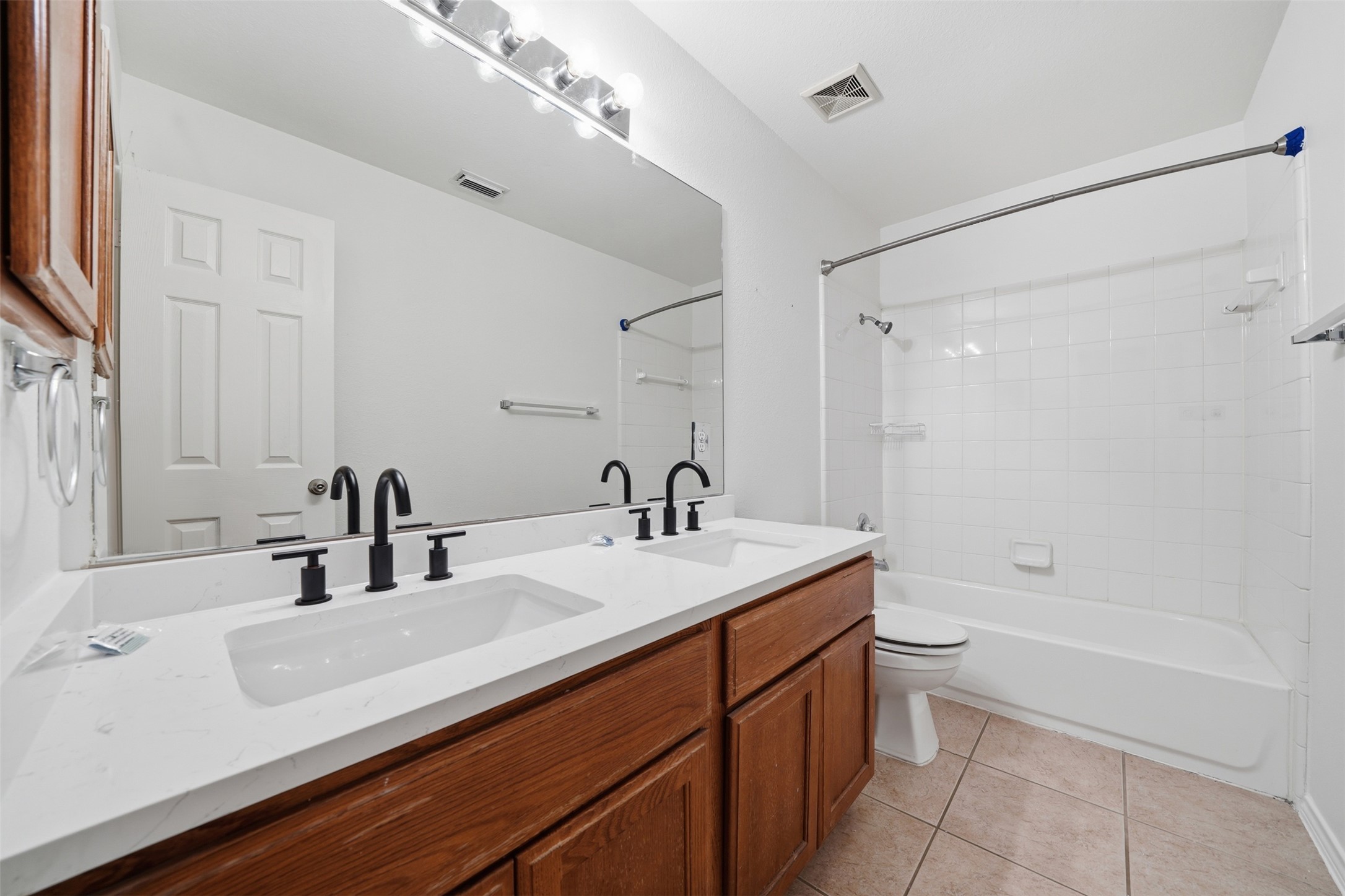 118 Invierno Street Kyle, TX 78640 - Photo 21 of 37 Double vanity with contemporary black fixtures and a tiled shower/tub combination.