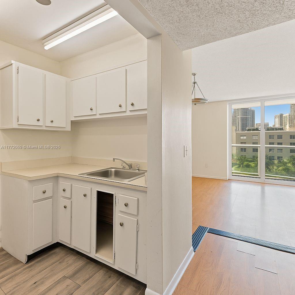 1035 West Avenue, Unit 507 Miami Beach, FL 33139 - Photo 4 of 22 a kitchen with stainless steel appliances granite countertop a sink and cabinets with wooden floor