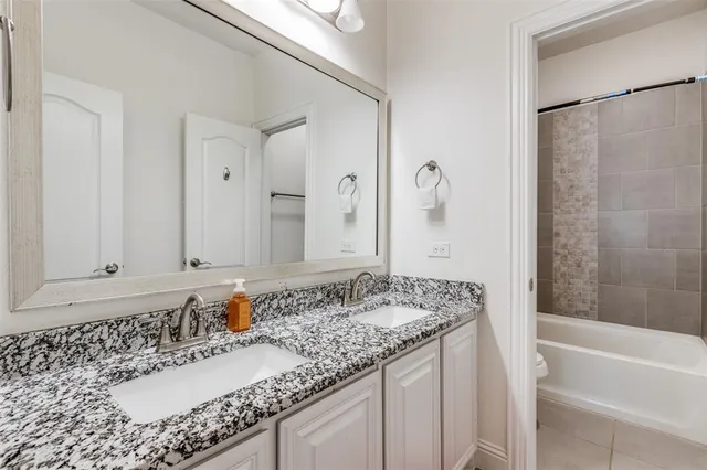 a bathroom with a granite countertop bathtub a sink and a mirror