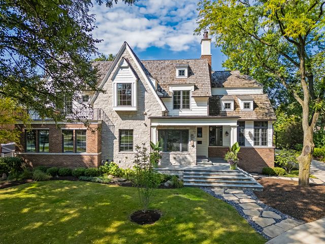 a front view of a house with garden and trees