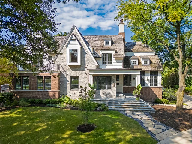 a front view of a house with garden and trees