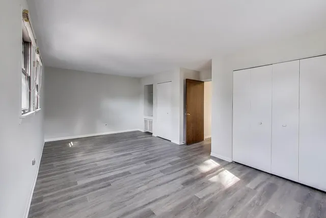 an empty room with wooden floor and window