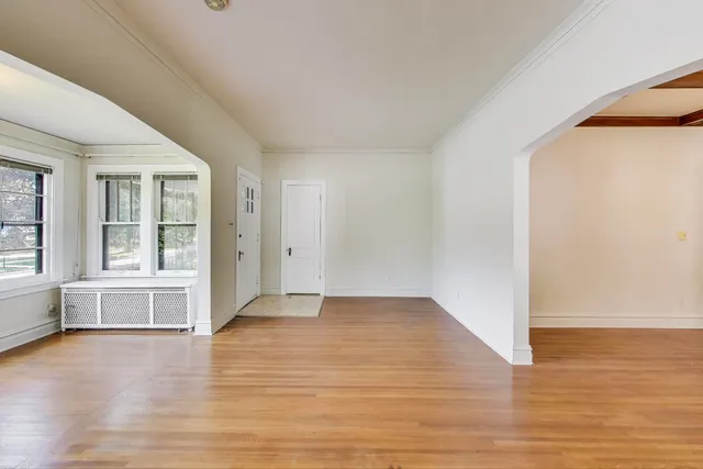 a view of an empty room with window and wooden floor
