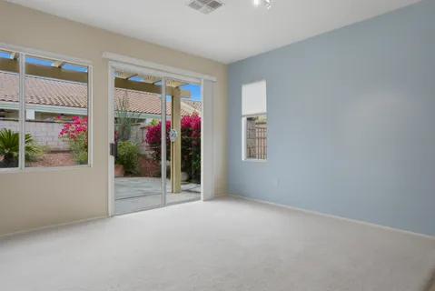 an empty room with windows and ceiling fan