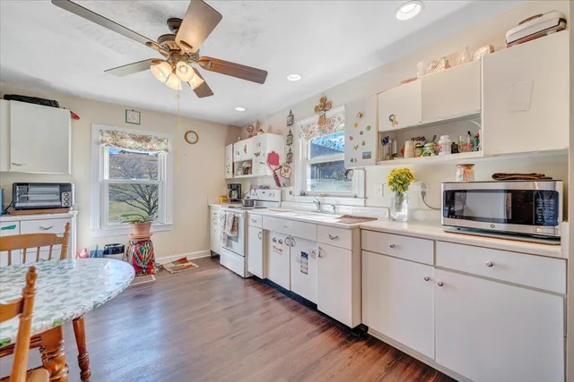 a kitchen with stainless steel appliances a sink a stove a refrigerator cabinets and wooden floor