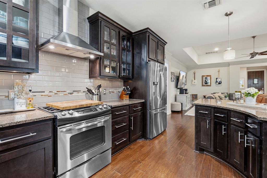 15317 Falconhead Grove Loop Austin, TX 78738 - Photo 11 of 29 A gourmet kitchen showcasing rich cabinetry, stainless steel appliances, and gleaming granite countertops.