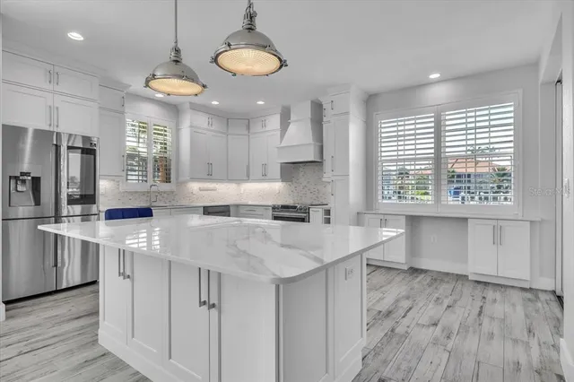 a large kitchen with kitchen island granite countertop a large window and white cabinets
