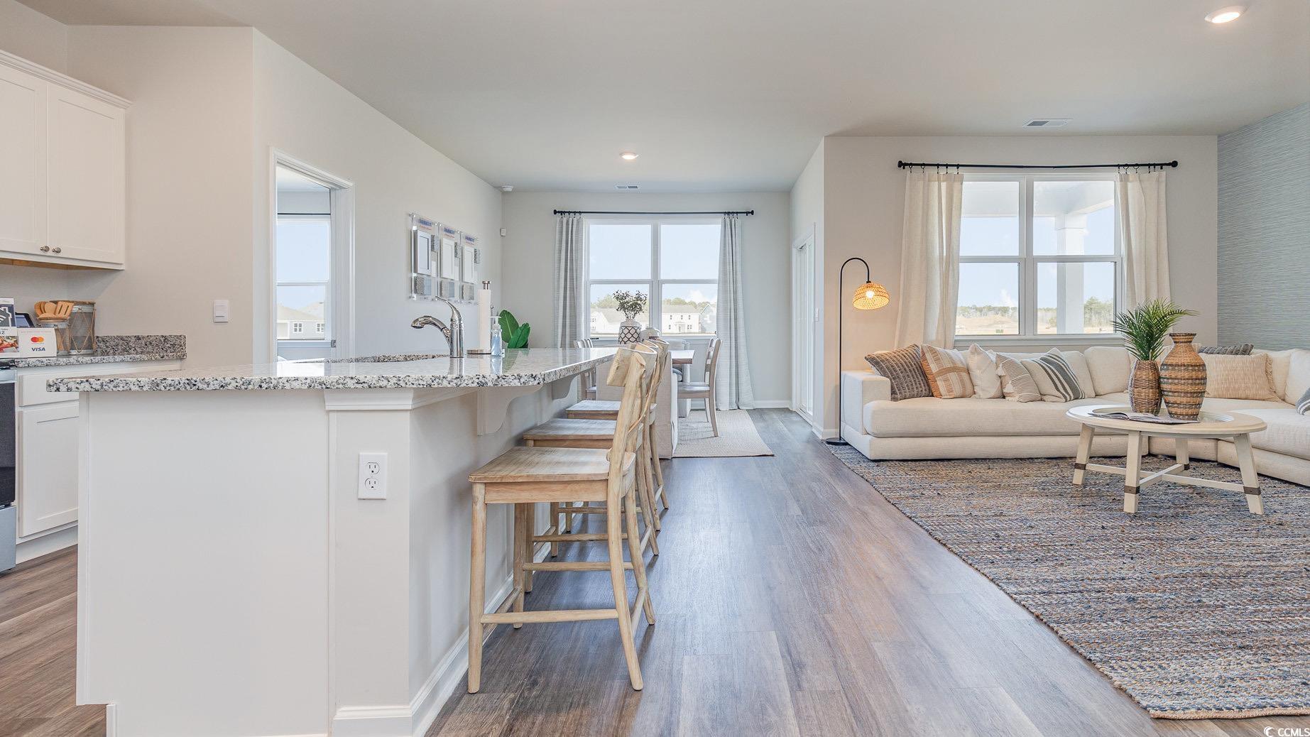 592 Duvall Street Longs, SC 29568 - Photo 28 of 28 Kitchen featuring open floor plan, an island with sink, dark wood-style flooring, light stone counters, and white cabinets