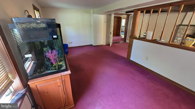 a view of a refrigerator in kitchen and an empty room with wooden floor