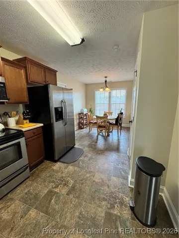 a kitchen with stainless steel appliances wooden cabinets a stove a sink a dining table and chairs