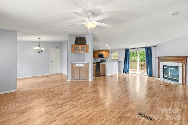 a view of an empty room with a kitchen and wooden floor