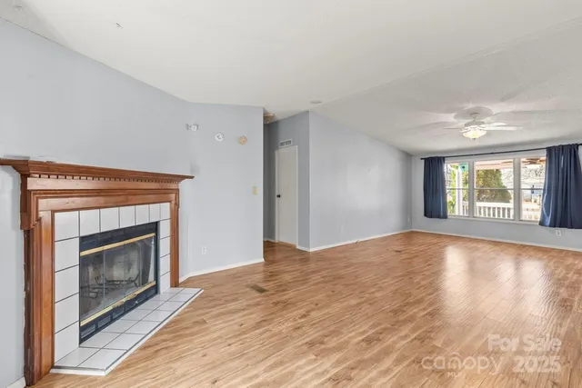 a view of empty room with wooden floor and fireplace