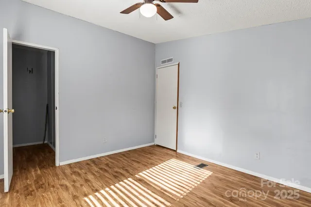 a view of a room with wooden floor and a ceiling fan