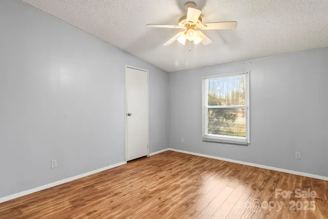 an empty room with a window and a fan