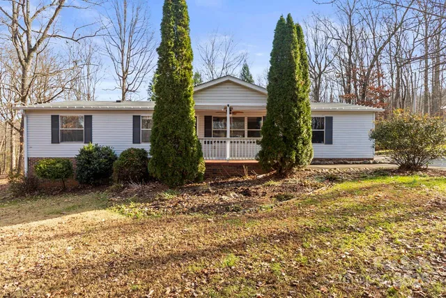 front view of house with a yard and trees