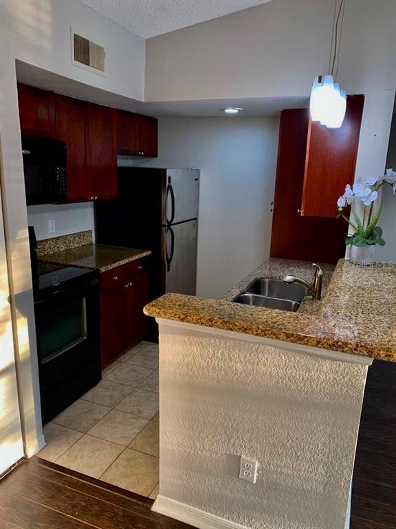 5152 Conroy Road, Unit 35 Orlando, FL 32811 - Photo 5 of 13 a kitchen with kitchen island granite countertop a sink stove and refrigerator
