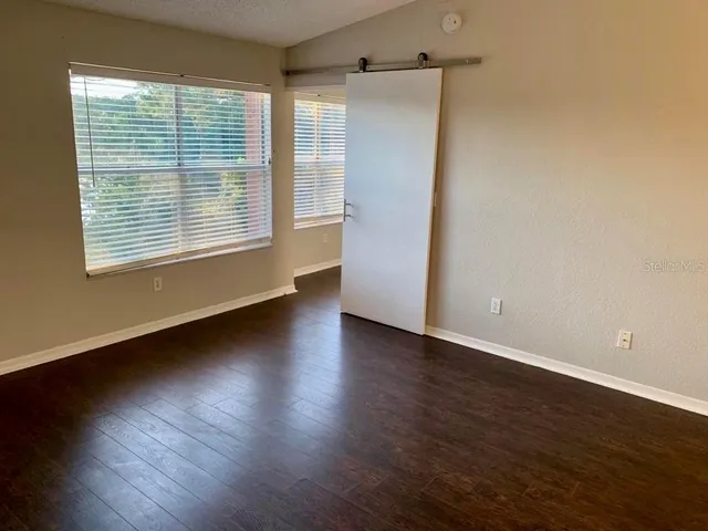 a view of an empty room with wooden floor and a window