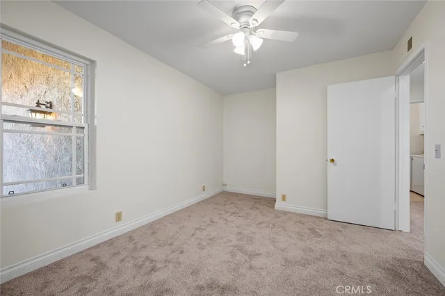 an empty room with chandelier fan and windows